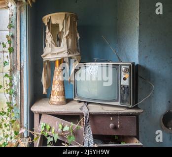 Alter Fernseher und Stuhl in einem verlassenen Haus. Stockfoto