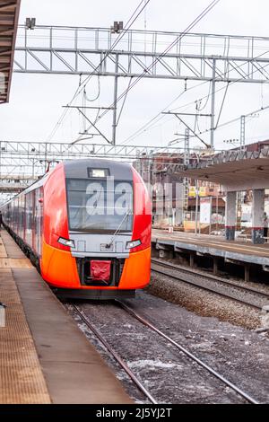 Moderne Hochgeschwindigkeitszug bewegt sich schnell entlang der Plattform. Stockfoto