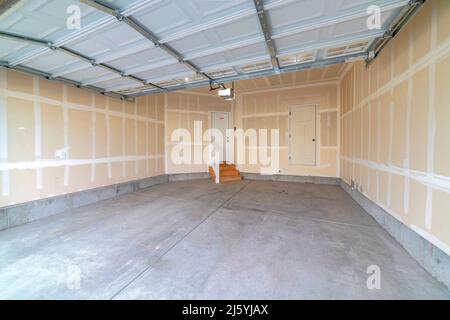 Innenraum einer unfertigen Garage mit automatischem Garagentor an der Decke Stockfoto
