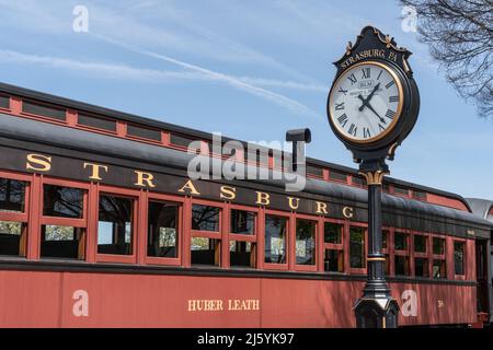 Strasburg, PA, USA - 20,2022. April: Zug fährt neben der Uhr am Bahnhof Strasburg Rail Road in Lancaster County, Pennsylvania. Stockfoto