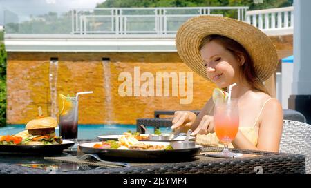 Eine Frau, die im Sommer im Hotelrestaurant zu Mittag oder zu Frühstück gegessen hat Stockfoto