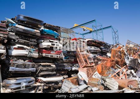 Gestapelte und zerkleinerte Autos und Stapel von Metallregalen auf einem Altmetall-Recyclinghof. Stockfoto