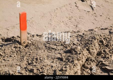 Vermesserspieß im Sand auf einer Baustelle. Stockfoto