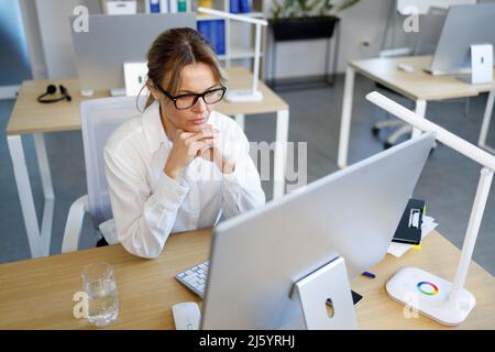 Konzentrierte Geschäftsfrau, die auf den Computerbildschirm schaut Stockfoto