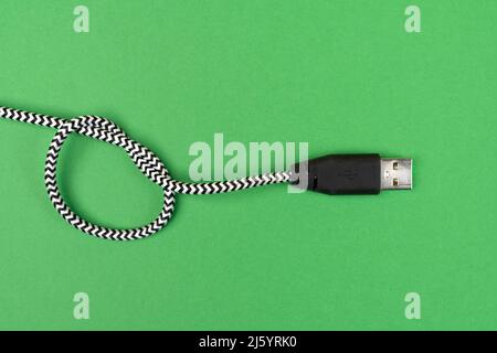 Ein USB-Kabel, das auf einer grünen Oberfläche verknotet ist Stockfoto
