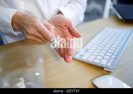 Nahaufnahme einer Geschäftsfrau, die eine Pille aus einer Blisterpackung nimmt Stockfoto