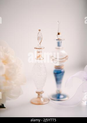 Schöne Vintage-Parfümflaschen auf weißem Tisch mit Blumen. Beauty- und Pflegekonzept Stockfoto