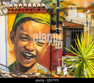 Bunte Wandgemälde an den Wänden des Hauses, Calle Parrilla. Lachend braun Junge Wandbild. Wall Street Art im Barrio Realejo, Granada Spanien Stockfoto