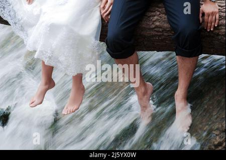 Hochzeitskonzept für den Sommer. Braut und Bräutigam sitzen beim Baden im Fluss. Glückliches Paar. Stockfoto