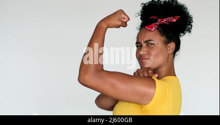 Afroamerikanische feministische Frau, die vor der Kamera posiert und dabei handelt, können wir es mit Arm tun Stockfoto