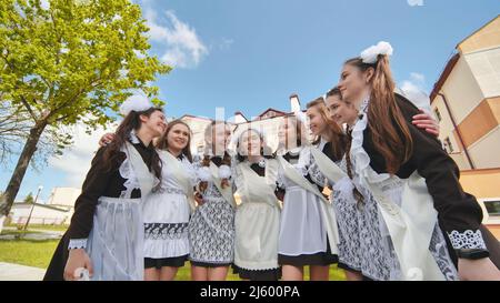 Lächelnde weibliche Absolventen posieren am letzten Tag des Schullebens. Stockfoto