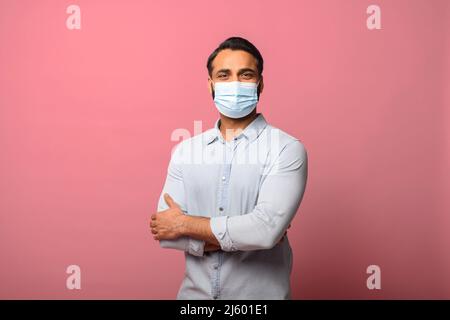 Porträt des wirksamen Schutzes gegen Coronavirus. Indischer Mann trägt eine medizinische Maske, um Infektionen, Atemwegserkrankungen wie Grippe zu verhindern. Innenaufnahme im Studio, rosa Hintergrund Stockfoto