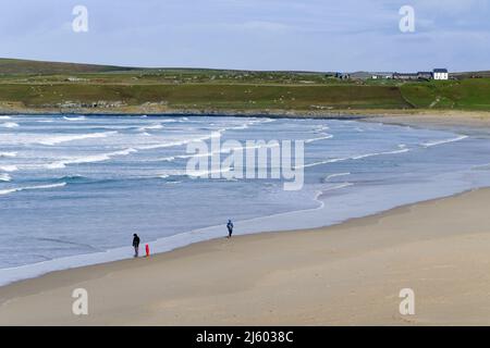 Ein Panoramablick auf die Machir Bay auf der Isle of Islay in den schottischen Inner Hebriden. Eine kleine Familiengruppe genießt den Strand und ein weißer Cottege steht an Stockfoto