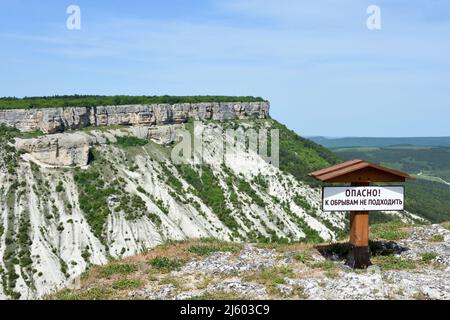 Großer Berg auf dem Chufut-Kale-Hochplateau mit Planke: 'Gefahr! Вo nähert euch nicht dem Abgrund!' Stockfoto