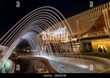 Außenansicht des vornehmen Saler Einkaufszentrums bei Nacht mit Springbrunnen, Valencia Spanien. Stockfoto