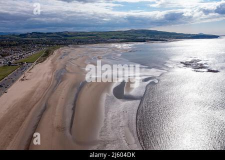 Ayr, Schottland, Großbritannien. 26. April 2022. IM BILD: Luftdrohnenansicht von oben auf den Ayr Beach mit Blick auf den Firth of Clyde und die Küstenstadt Ayr. Westlich von Schottland sah man strahlenden Sonnenschein und blauen Himmel an der Küste am Ayr Beach. Menschen gehen spazieren und ein Reiter nimmt ihr Pferd durch einen Galopp im kühlen Meerwasser. Quelle: Colin Fisher/Alamy Live News Stockfoto