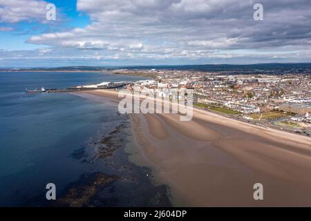 Ayr, Schottland, Großbritannien. 26. April 2022. IM BILD: Luftdrohnenansicht von oben auf den Ayr Beach mit Blick auf den Firth of Clyde und die Küstenstadt Ayr. Westlich von Schottland sah man strahlenden Sonnenschein und blauen Himmel an der Küste am Ayr Beach. Menschen gehen spazieren und ein Reiter nimmt ihr Pferd durch einen Galopp im kühlen Meerwasser. Quelle: Colin Fisher/Alamy Live News Stockfoto