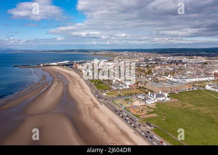 Ayr, Schottland, Großbritannien. 26. April 2022. IM BILD: Luftdrohnenansicht von oben auf den Ayr Beach mit Blick auf den Firth of Clyde und die Küstenstadt Ayr. Westlich von Schottland sah man strahlenden Sonnenschein und blauen Himmel an der Küste am Ayr Beach. Menschen gehen spazieren und ein Reiter nimmt ihr Pferd durch einen Galopp im kühlen Meerwasser. Quelle: Colin Fisher/Alamy Live News Stockfoto