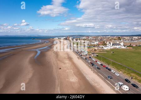 Ayr, Schottland, Großbritannien. 26. April 2022. IM BILD: Luftdrohnenansicht von oben auf den Ayr Beach mit Blick auf den Firth of Clyde und die Küstenstadt Ayr. Westlich von Schottland sah man strahlenden Sonnenschein und blauen Himmel an der Küste am Ayr Beach. Menschen gehen spazieren und ein Reiter nimmt ihr Pferd durch einen Galopp im kühlen Meerwasser. Quelle: Colin Fisher/Alamy Live News Stockfoto