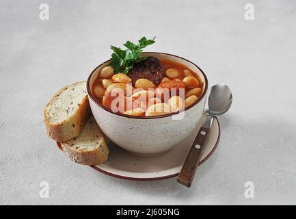 Traditionelles Rezept von Bohnen mit Chorizo und Blutwurst von Fabada Asturiana auf einem weißen Tisch. Selektiver Fokus Stockfoto