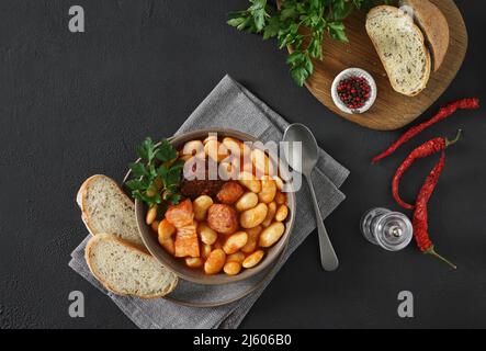 Traditionelles Rezept von Bohnen mit Chorizo und Blutwurst von Fabada Asturiana auf einem dunklen Tisch. Draufsicht. Kopierraum Stockfoto