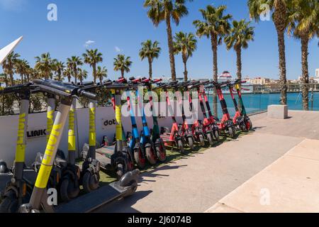 Parkplatz für Elektroroller, an der Strandpromenade des Hafens von Malaga. Link, Dott, VOI Motorroller zur Miete auf der Promenade 'Muelle Uno'. Stockfoto