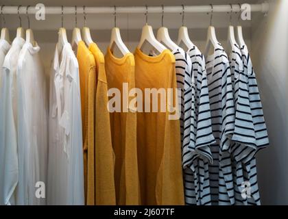 Kleidung, T-Shirts, Kleider hängen an einem Kleiderbügel im Kleiderschrank Stockfoto