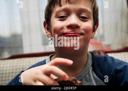 Porträt eines lustigen niedlichen kaukasischen Jungen, der Schokolade isst Stockfoto