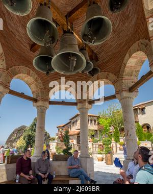 Menschen, die in einem Kiosk vor der Kirche des Klosters Agioi Pantes Meteora, Griechenland, auf einer Kuppel sitzen und die Glocken anstarren Stockfoto