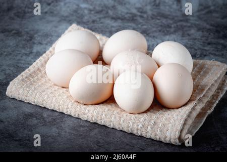 Hühnereier auf beigefarbenem Handtuch auf grauem Hintergrund Stockfoto