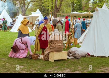 Freunde in historischen Kostümen sprechen bei einer Nachstellung eines mittelalterlichen Lagers auf dem Gelände von Tamworth Castle, England, Großbritannien. Stockfoto