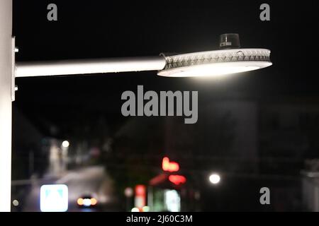 Heiningen, Deutschland. 26. April 2022. Auf einer Straßenlampe gibt es eine Steuerung, um die Helligkeit zu regulieren. An der örtlichen Durchgangsstraße soll die Beleuchtung an das nächtliche Verkehrsaufkommen angepasst werden, so dass Insekten geschützt werden sollen. Die Tiere werden vom Licht angezogen und sterben in den Leuchten oder kreisen vor ihnen, bis sie erschöpft sind. Ein Kamerasystem wird auch verwendet, um die Insekten zu zählen. Quelle: Stefan Puchner/dpa/Alamy Live News Stockfoto