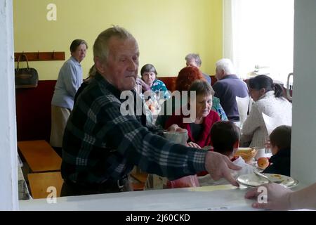 Non Exclusive: DOVHOPOLE, UKRAINE - 25. APRIL 2022 - ein alter Mann legt einen leeren Teller in einer örtlichen Schule ab, die die Heimat der Vertriebenen aus Kyi wurde Stockfoto