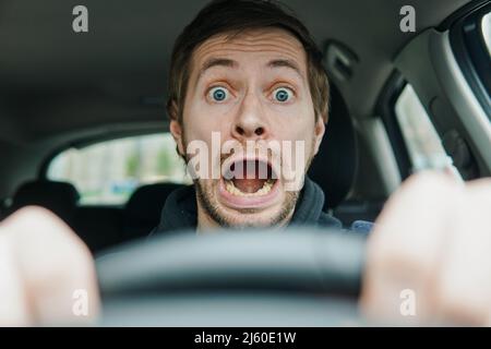 Nahaufnahme eines schockierten männlichen Fahrers mit überraschendem Gesicht und offenem Mund. Stockfoto