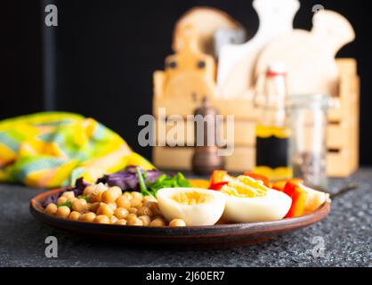 Salat: Gericht mit Geschmack aus Tomaten, Gurke, Rotkohl und Petersilie, Kichererbsen, hart gekochtem Ei und Tahini-Sauce Stockfoto