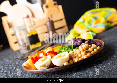 Salat: Gericht mit Geschmack aus Tomaten, Gurke, Rotkohl und Petersilie, Kichererbsen, hart gekochtem Ei und Tahini-Sauce Stockfoto