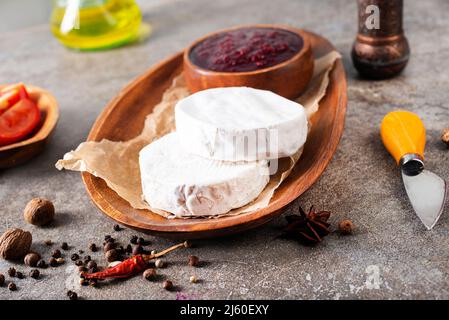 Camembert Käse mit Feigen, Himbeermarmelade. Rundbrie oder Camambert-Käse auf Schneidebrett Stockfoto