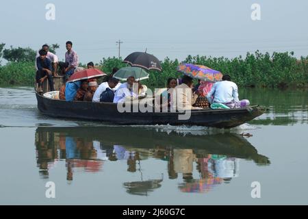 Passagiere, die mit einem Holzboot in Tanguar Haor in Sunamganj reisen. Tanguar Haor ist ein Feuchtgebiet im Bezirk Sunamganj im Großraum Sylhet in Bangladesch. Dieser Haor erstreckt sich über eine Fläche von etwa 100sq km und ist das zweitgrößte Süßwasser-Feuchtgebiet in Bangladesch. Für die Einheimischen ist der Haor auch als Nayakuri Kandar Chayakuri Beel bekannt. Stockfoto