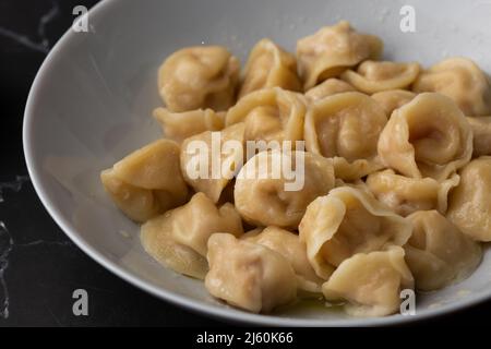Fleischknödel, hausgemachte russische Pelmeni in Schüssel isoliert auf hellem Hintergrund mit Schneideweg. Stockfoto