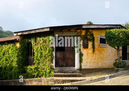 Juayua, El Salvador - 29. Januar 2022: Ansicht eines Hotels in Juayua, El Salvador in touristischer Lage. Bauen mit Klettereifeu auf einer Seite und yel Stockfoto