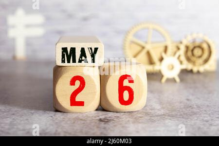 Mai. Mai 26 Holzwürfelkalender mit unscharfen Objekten auf dem Hintergrund. Stockfoto