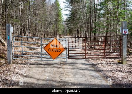 Ein verschlossenes Metalltor mit einem geschlossenen Straßenschild auf einer Forststraße in der Speculator Tree Farm in den Adirondack Mountains, NY USA, im Frühjahr Stockfoto