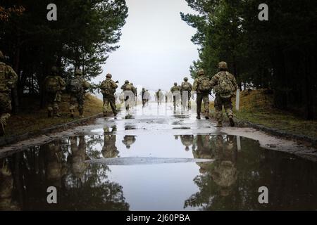 US-Soldaten, die dem Hauptquartier und dem Hauptquartier Battery, dem Bataillon 3., dem Artillerieregiment 29. (3-29. FA), dem Kampfteam der 3. Panzerbrigade und der Infanterie-Division 4. zugewiesen wurden, marschieren in die Reichweite, bevor sie ihre Waffen in Torun, Polen, am 20. April 2022 zerschießen. Die FA von 3-29 ist unter anderem dem V Corps, dem amerikanischen Vorbereitungs-Korps in Europa, zugewiesen, das mit NATO-Verbündeten und regionalen Sicherheitspartnern zusammenarbeitet, um kampfglaubwürdige Kräfte bereitzustellen und gemeinsame, bilaterale und multinationale Trainingseinheiten durchzuführen. (USA Armee-Nationalgarde Foto von Staff Sgt. Gabriel Rivera) Stockfoto