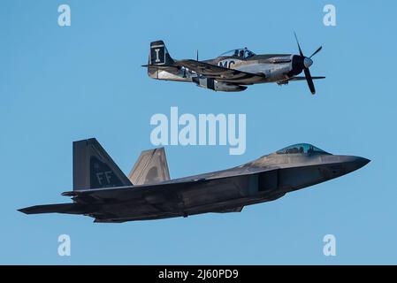 Ein Heritage Flight, bestehend aus einem P-51D Mustang aus dem Zweiten Weltkrieg und einem modernen F-22 Raptor der US Air Force, führt eine Luftdemonstration über dem Ohio River in der Innenstadt von Louisville, Ky., 23. April 2022 im Rahmen der Flugshow Thunder over Louisville durch. Die diesjährige Veranstaltung feierte den 75.. Jahrestag der US-Luftwaffe. (USA Foto der Air National Guard von Dale Greer) Stockfoto