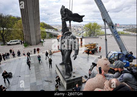 Kiew, Ukraine. 26. April 2022. Arbeiter demontieren das sowjetische Denkmal der ukrainisch-russischen Freundschaft, das 1982 als Symbol der Wiedervereinigung der Ukraine und Russlands während des russischen Einmarschs in die Ukraine errichtet wurde. Nach der Eskalation des Russland-Ukraine-Krieges kündigte Kiews Bürgermeister Witaliy Klitschko am 25. April 20222 an, dass die Skulpturenkomponente des Denkmals entfernt und der riesige Bogen über den Arbeitern umbenannt werden würde. Kredit: SOPA Images Limited/Alamy Live Nachrichten Stockfoto