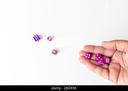 Rollende Würfel in der Hand und auf einem weißen Tisch Stockfoto