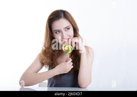 Hübsche junge Dame spielerisch bereit, einen bunten Lutscher schmecken, auf weißem Hintergrund - Stock Foto Stockfoto