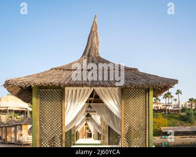 Romantischer Pavillon am Strand mit Palmen am Ufer. Stockfoto