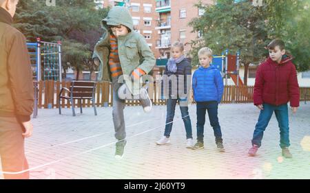 Kinder Überspringen auf chinesische Springen elastische Kordel im Hof Stockfoto