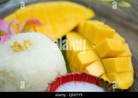 Klebriger Reis serviert auf Bananenblättern mit süßem Barracuda Mango und Kokosmilch. Stockfoto